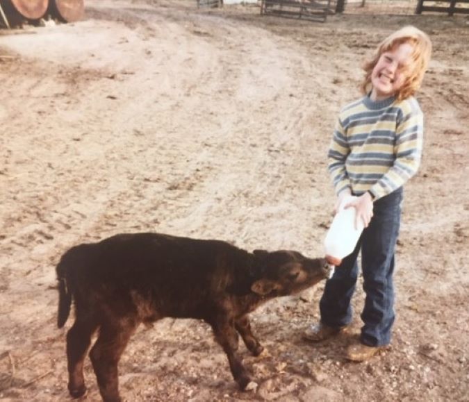 Lambley bottle-feeding a calf in her childhood 